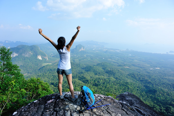 Woman on the top of a mountain with her airms raised in success