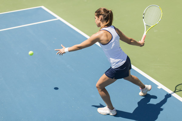 woman playing tennis on the courts ready to swing and hit the ball